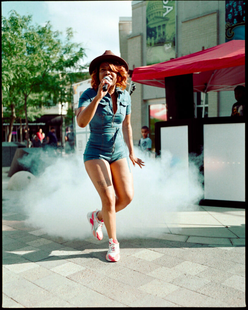Portrait of a woman hip-hop artist performing with a fog machine in downtown Madison, Wisconsin, on a warm summer afternoon