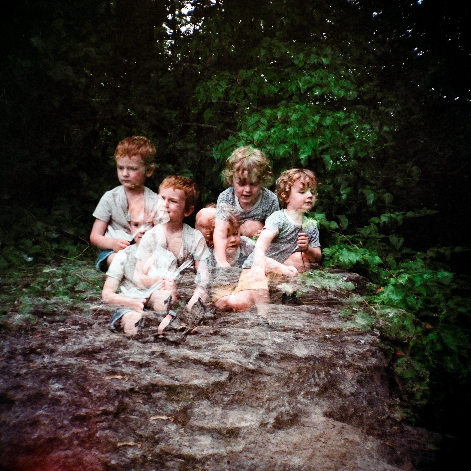 Triple exposure of two children having a picnic in a forest