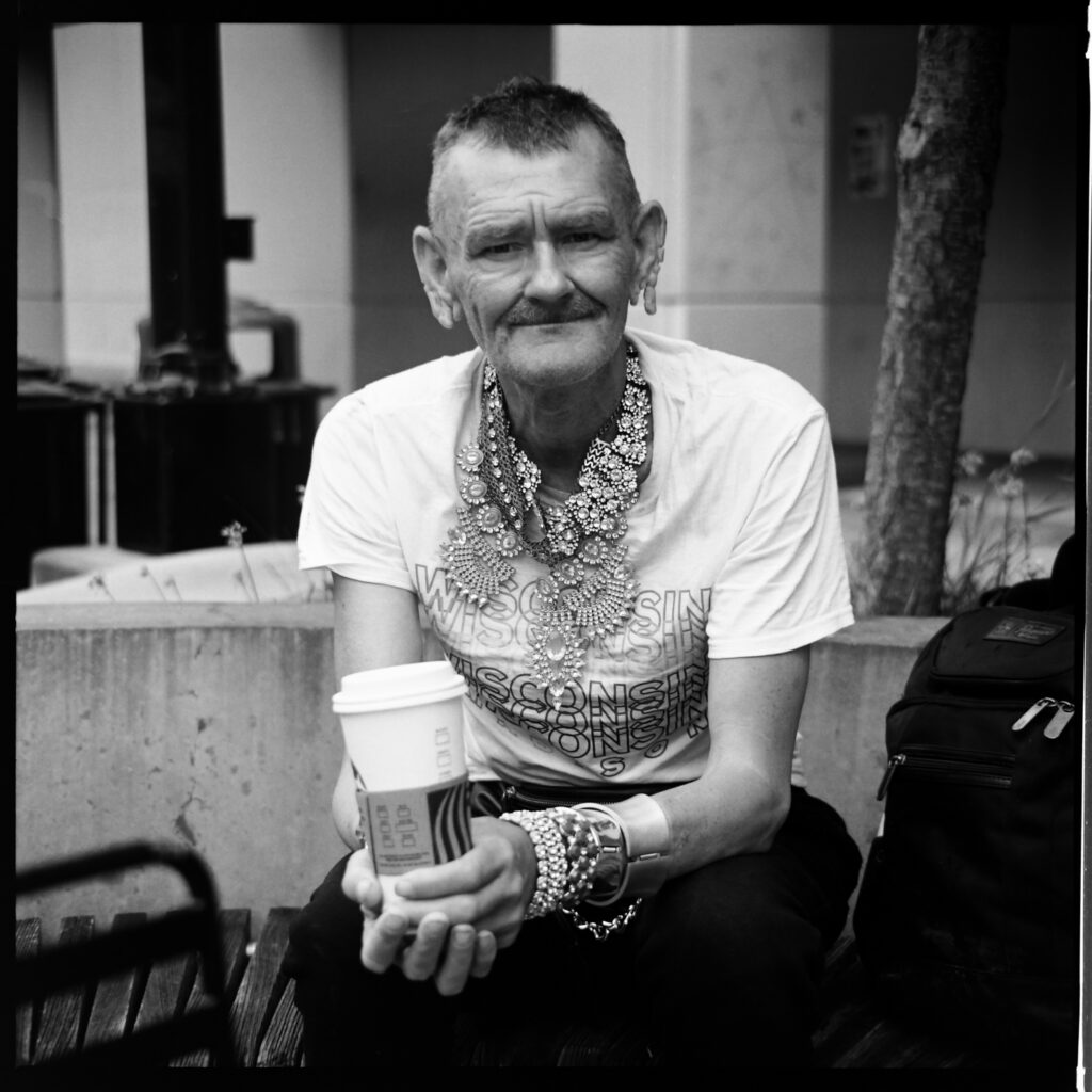 Portrait of a homeless man wearing a lot of necklaces and bracelets
