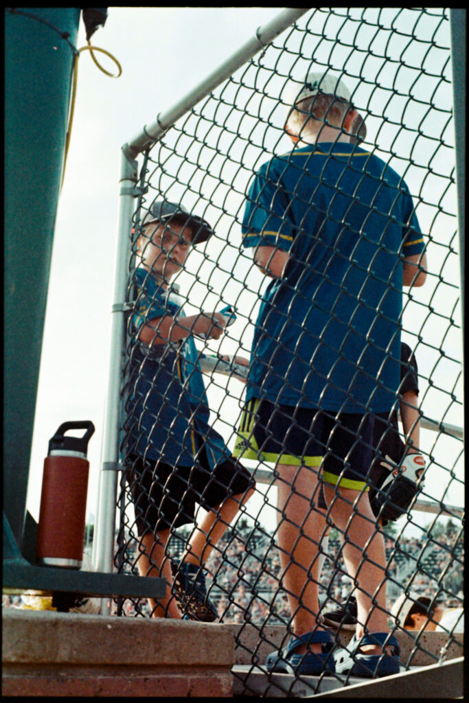 Three kids in the bleacher exchanging thoughts at the end of a Madison Mallard's baseball game