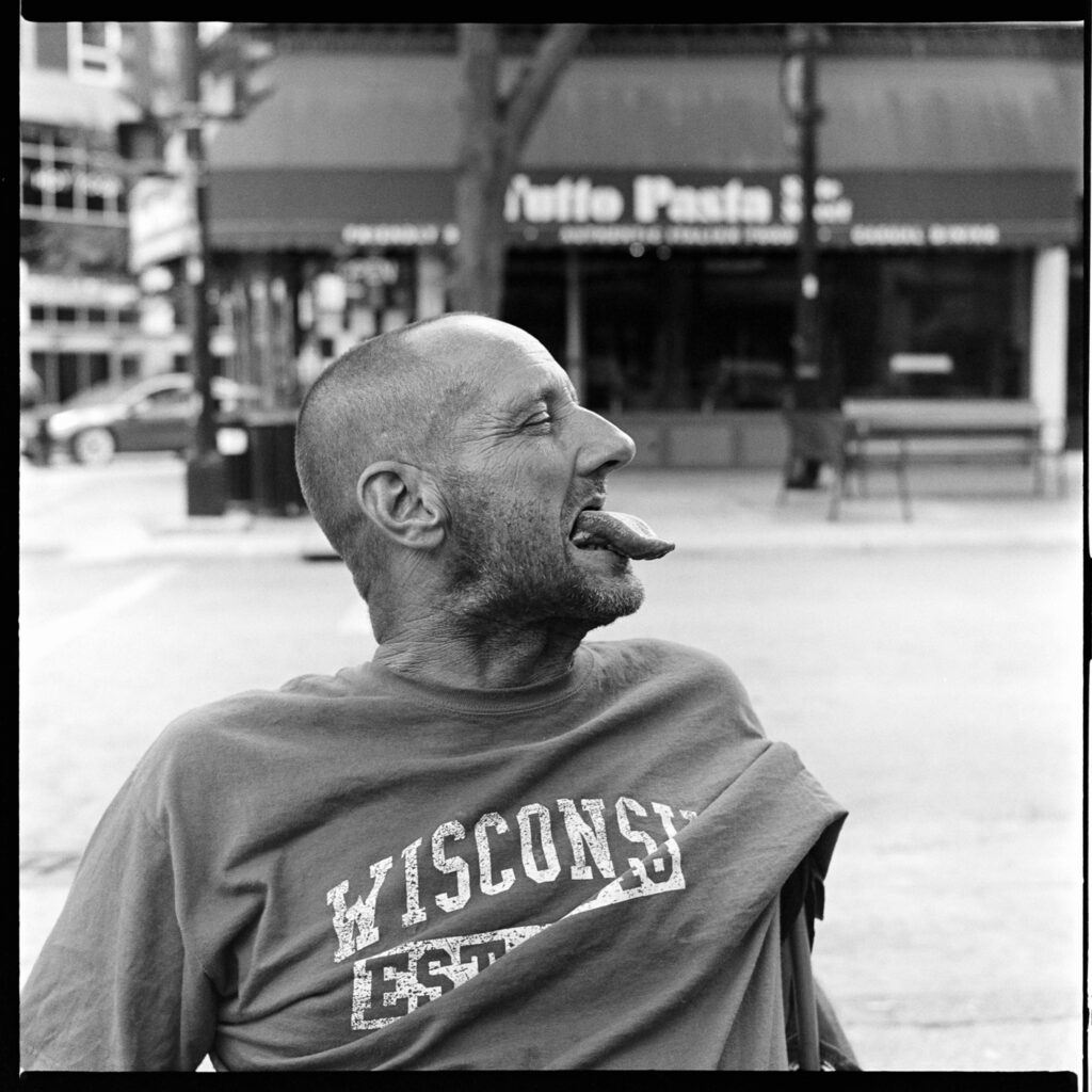 Portrait of Jason, homeless man on State Street, pulling his tongue out playfully for the photographer to photograph