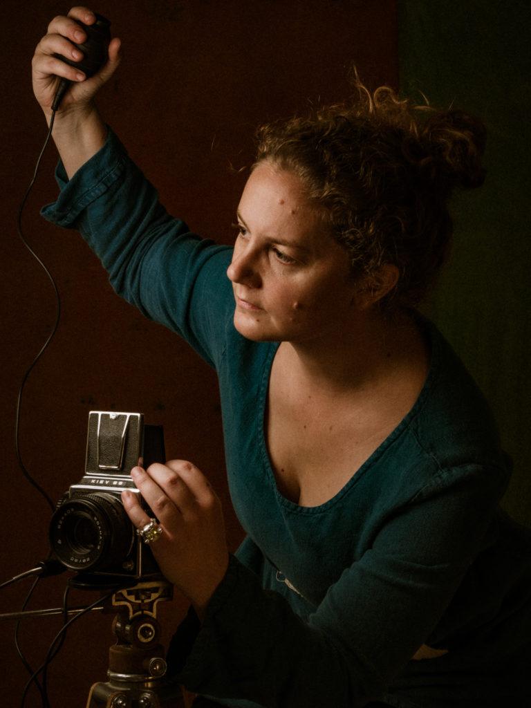 Self-portrait of Madison Photographer Flavia Fontana Giusti holding a bulb remote shutter release with a medium format camera