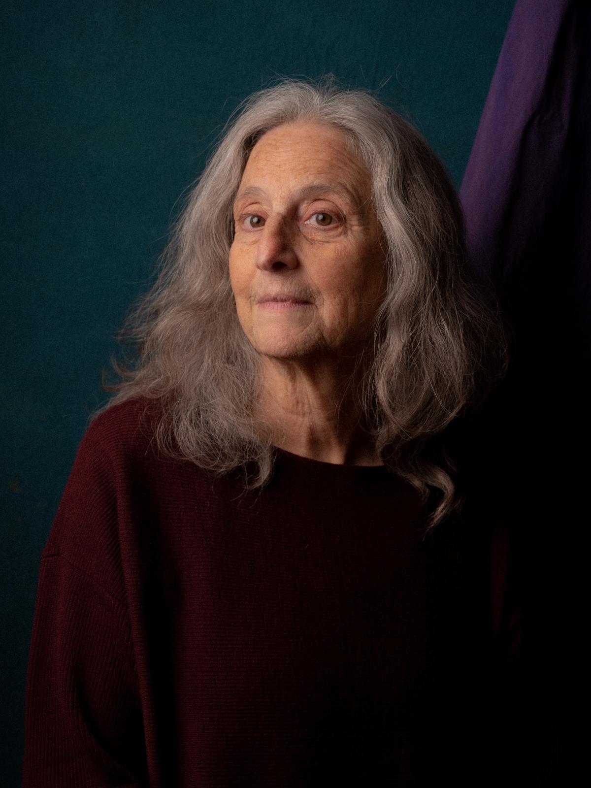 Photographic portrait of an older lady with beautiful long grey hair, looking smart, gaze slightly to the left, a slight smile
