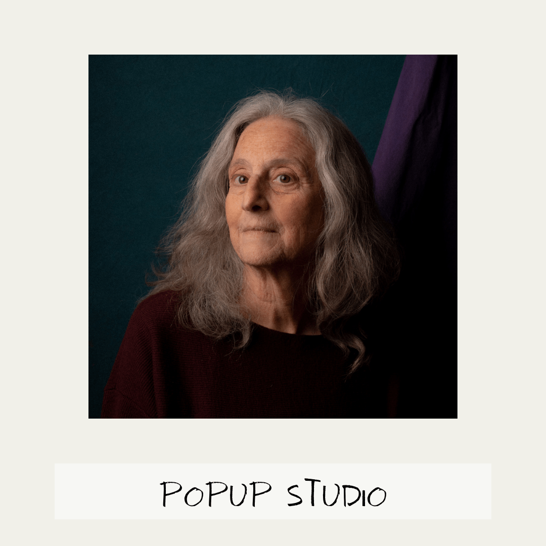 headshot portrait photograph of an elderly lady with beautiful long grey hair framing her face