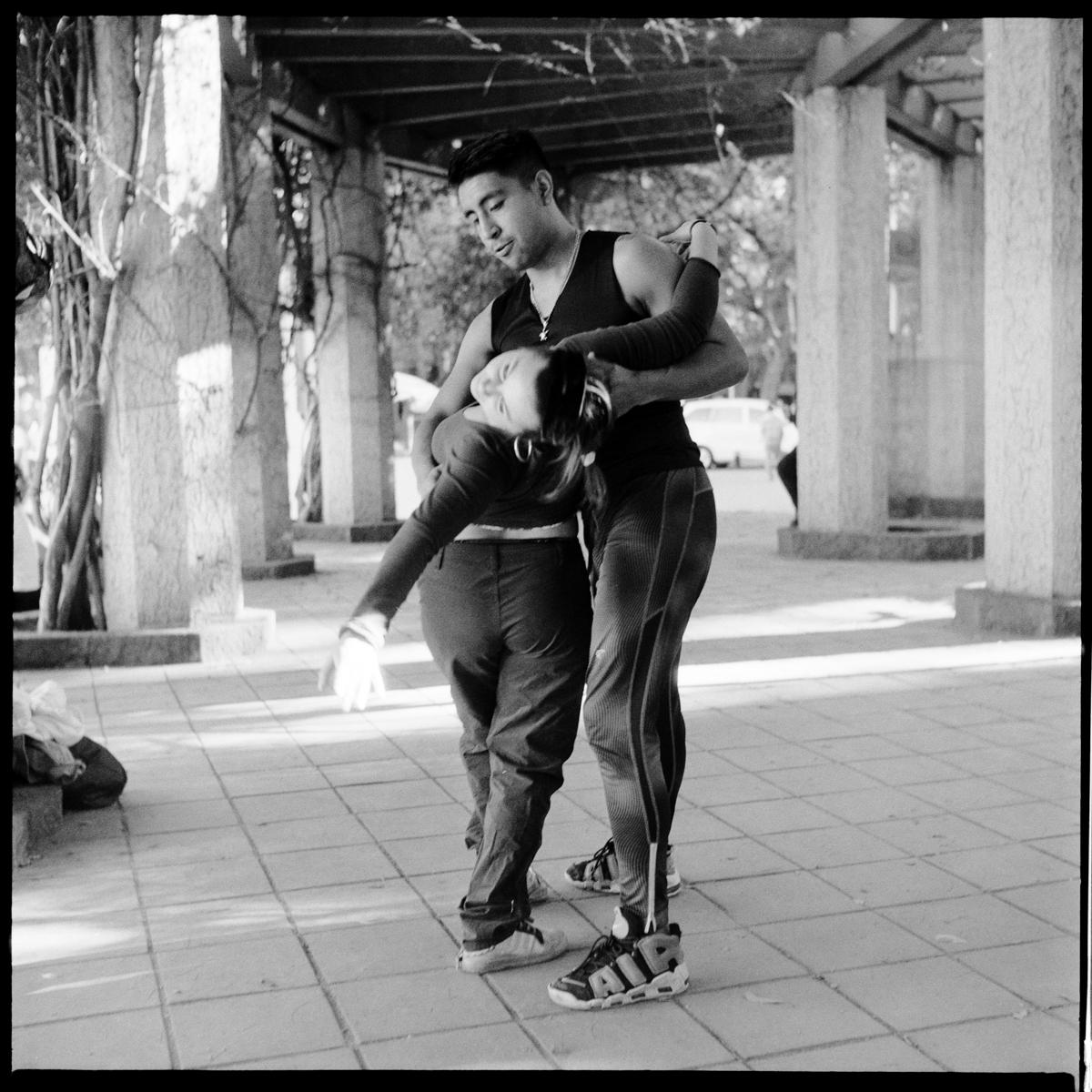 analog black-and-white street photograph of a couple dancing in Parque México on a Saturday afternoon
