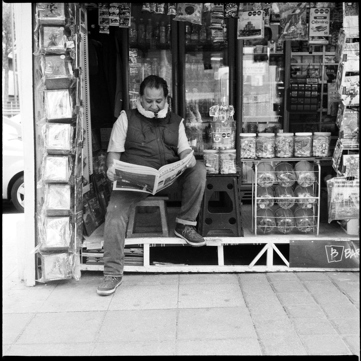 analog black-and-white street photograph of a man reading the newspaper in Mexico City