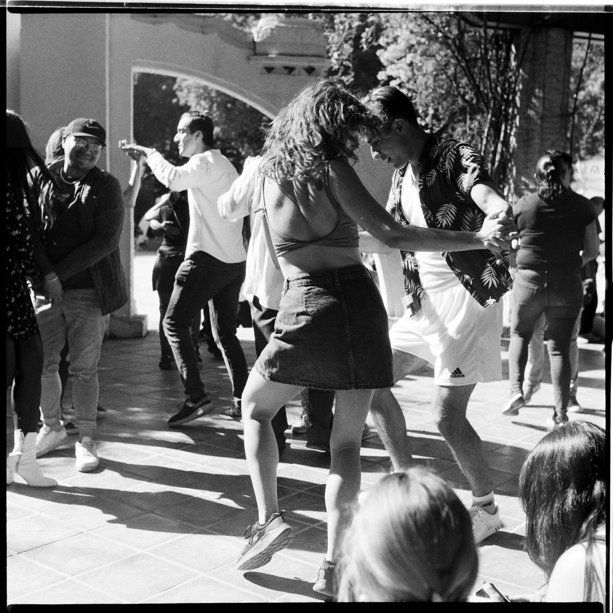 analog black-and-white street photograph of a couple dancing in Parque México on a Saturday afternoon