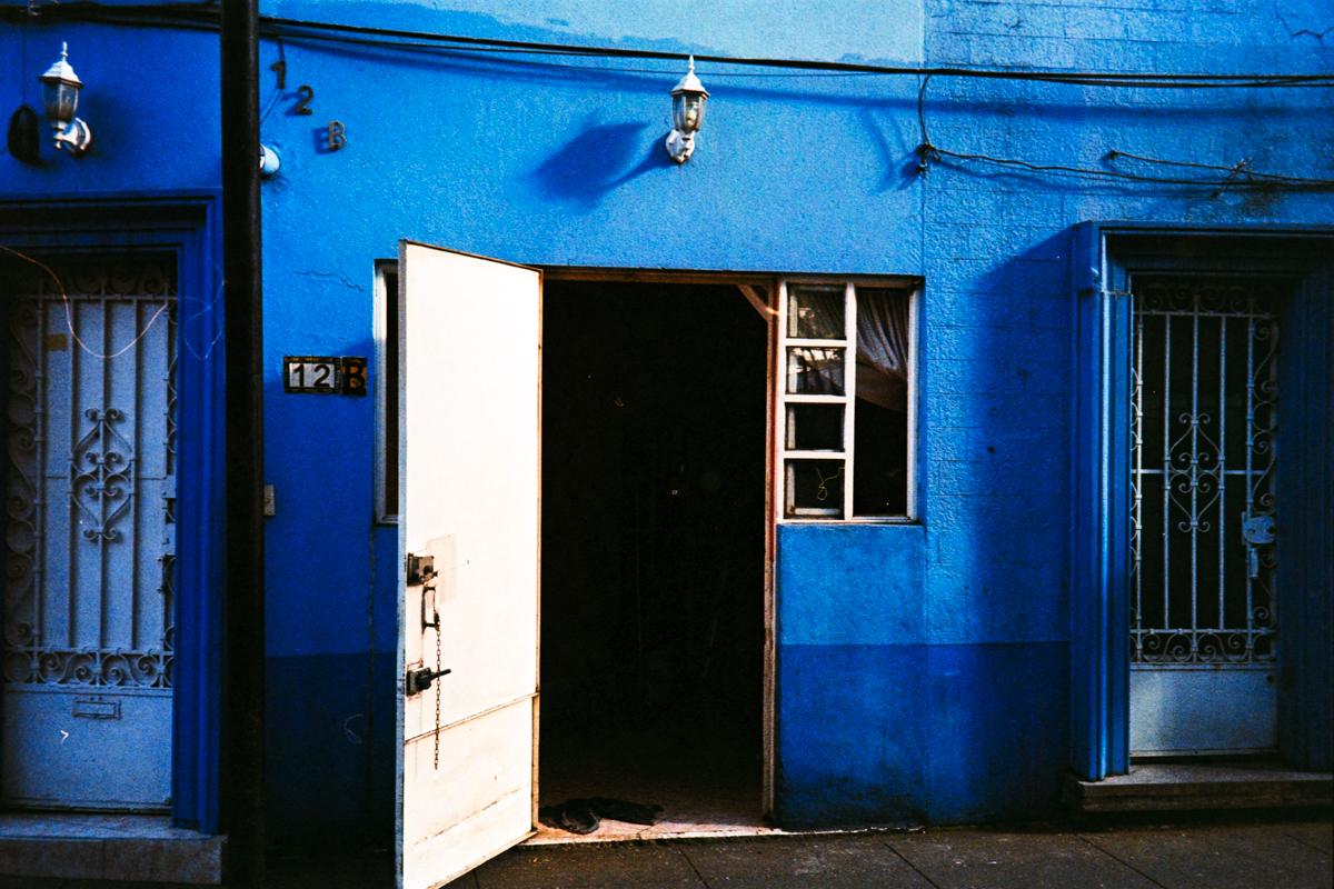 photograph of a blue house with open white door in the low evening light in Mexico City at dusk