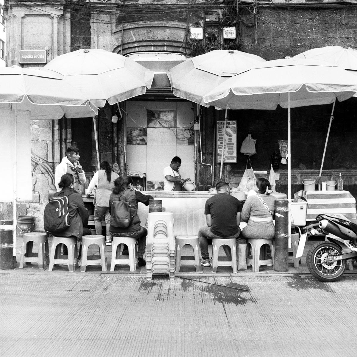 analog black-and-white street photograph of a street food stand in Mexico City's historic center