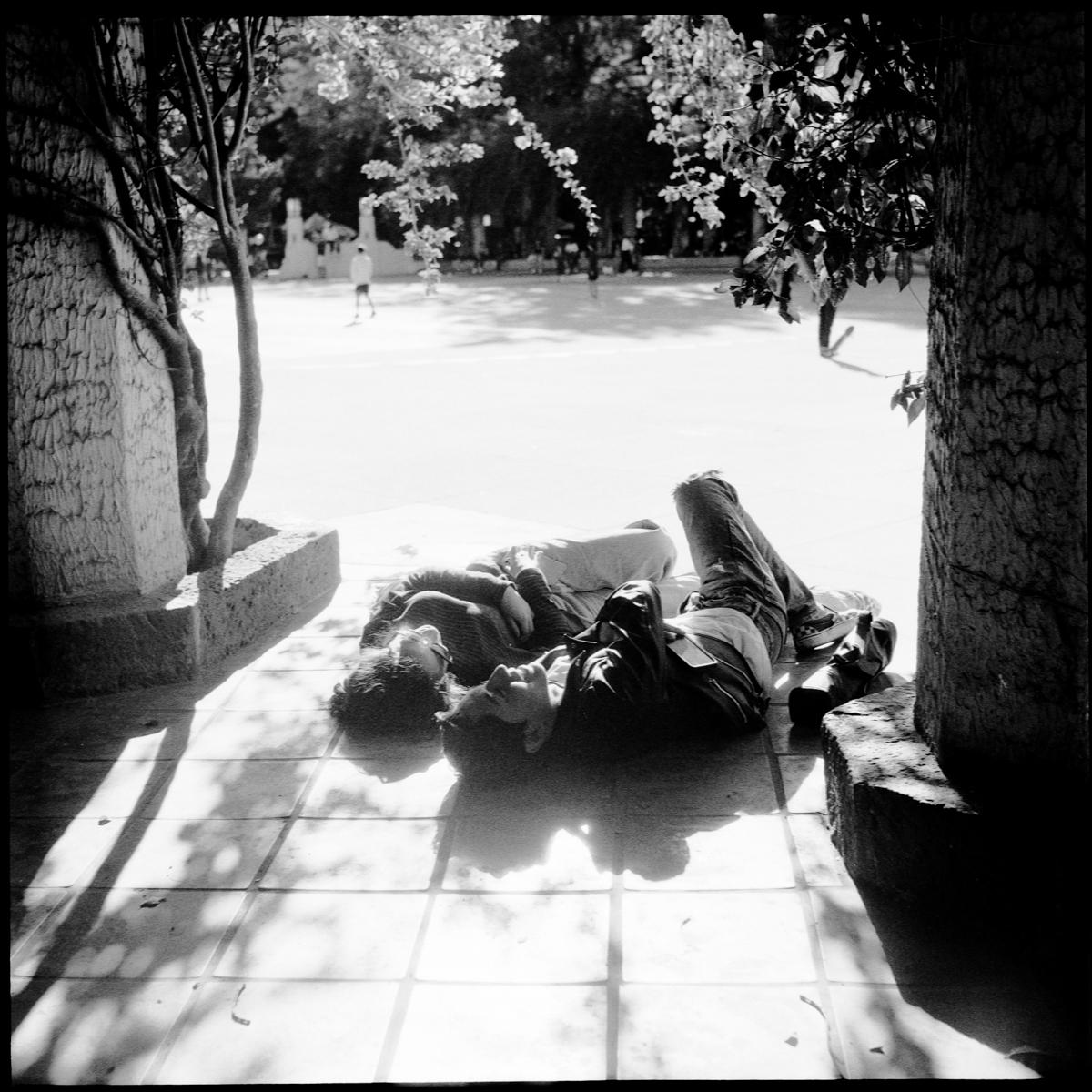 analog black-and-white street photograph of a couple making out in Parque México on a Saturday afternoon